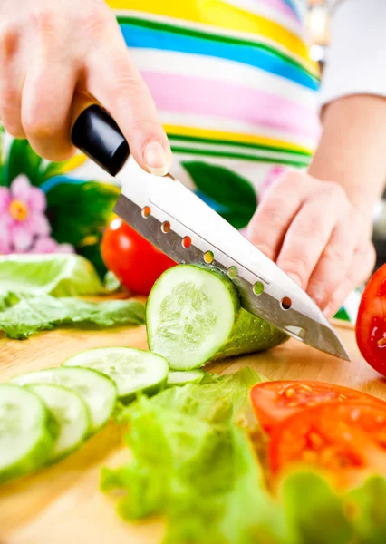 新鮮な野菜の後ろにキュウリを切る女性の手 — ストック写真