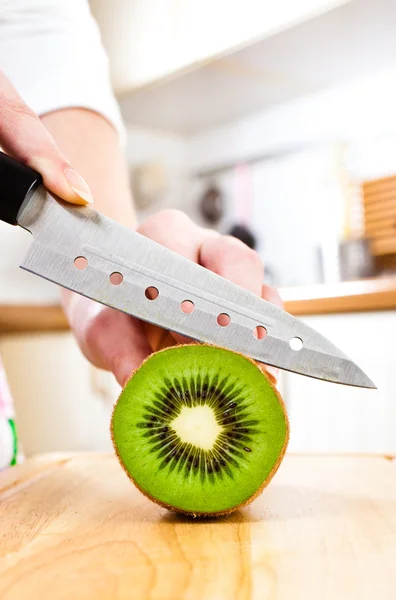 Las manos de la mujer cortando kiwi — Foto de Stock