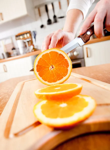 Vrouwenhanden die oranje snijden — Stockfoto