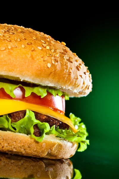 Tasty and appetizing hamburger on a darkly green — Stock Photo, Image