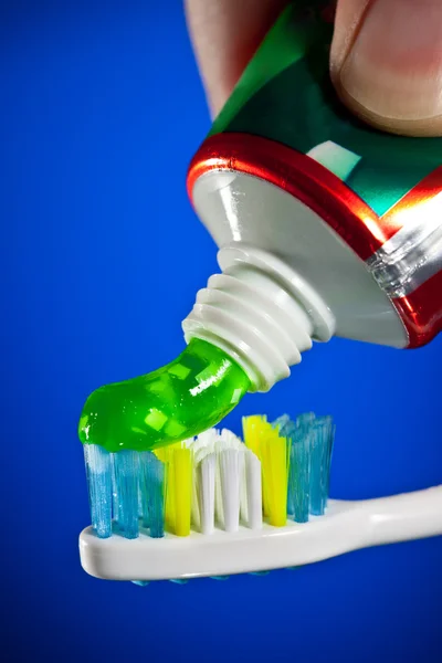 Zahnpasta Wird Auf Eine Zahnbürste Auf Dunkelblauem Hintergrund Gepresst — Stockfoto