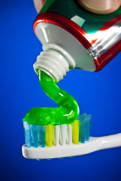 Zahnpasta Wird Auf Eine Zahnbürste Auf Dunkelblauem Hintergrund Gepresst — Stockfoto