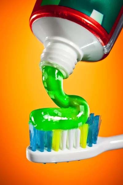 Toothpaste Being Squeezed Toothbrush Orange Background — Stock Photo, Image