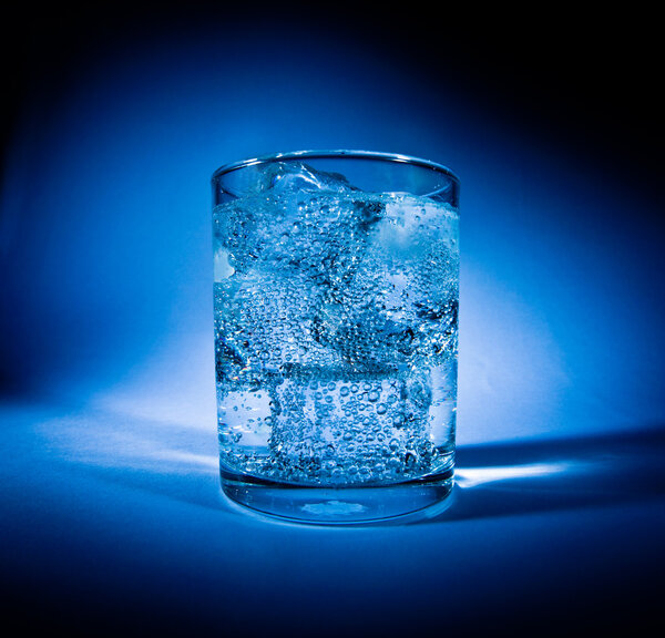 Glass of water with ice on a dark blue background