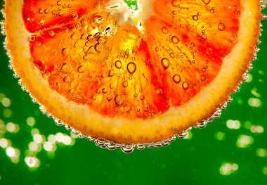 fresh red orange falls in water on a green background clipart