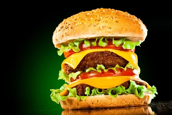Tasty and appetizing hamburger on a darkly green — Stock Photo, Image