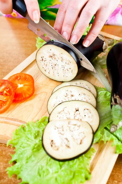 Woman's hands cutting aubergine eggplant — Stock Photo, Image