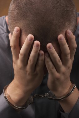 Arrested in handcuffs covered his face with his hands. clipart