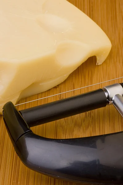 在木桌子上的瑞士奶酪切片和奶酪切片器 — 图库照片
