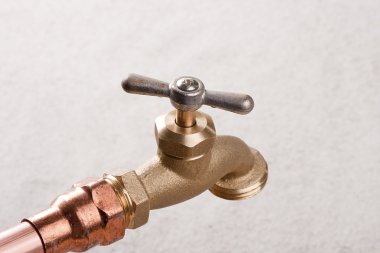 Bronze faucet attached to the water system of copper pipes. clipart