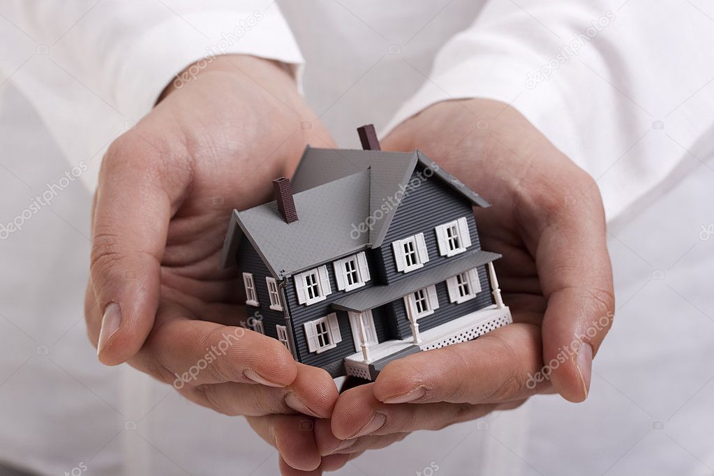 Man in white holding a model of a house in his hands.