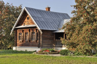 Beautiful wooden house with porch, flower bed and rowan-trees clipart