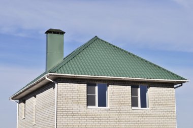 Green roof of white brick house clipart