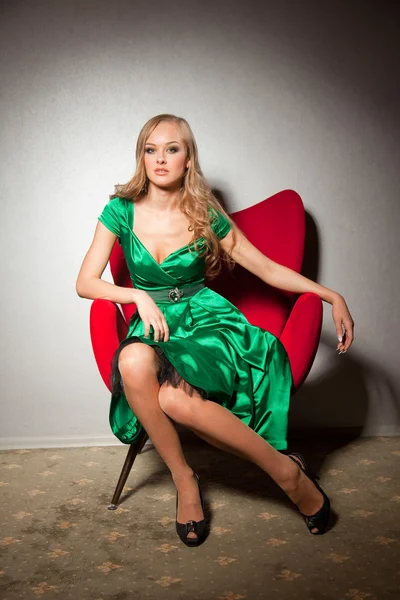 Elegantes Mädchen sitzt auf rotem Sofa — Stockfoto