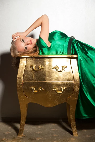 Девушка, лежащая на золотом столе — стоковое фото