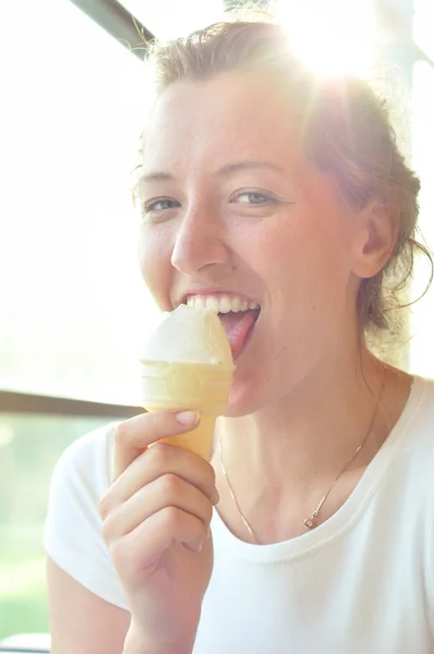 Gelukkig jonge vrouw is het eten van ijs in café — Stockfoto