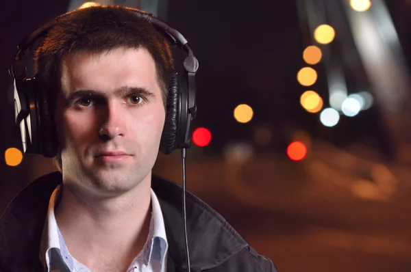 Hombre escuchando música en la calle nocturna de la ciudad — Foto de Stock