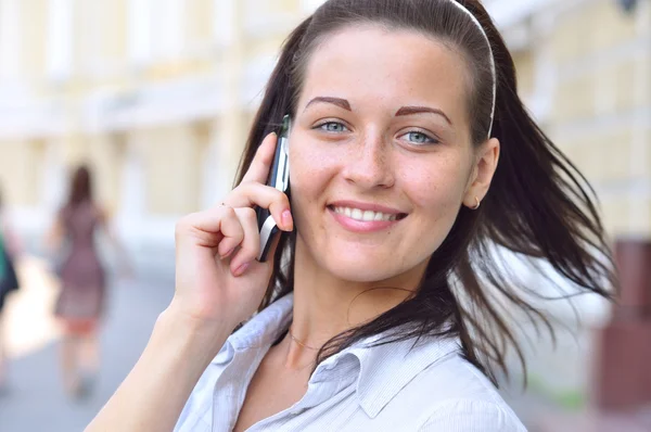 Krásná usměvavá žena mluví telefon na slunečné ulici — Stock fotografie