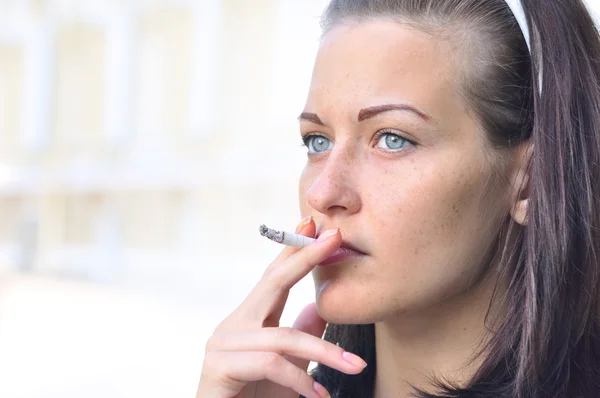 一个漂亮的女人在街上吸烟的特写 — 图库照片