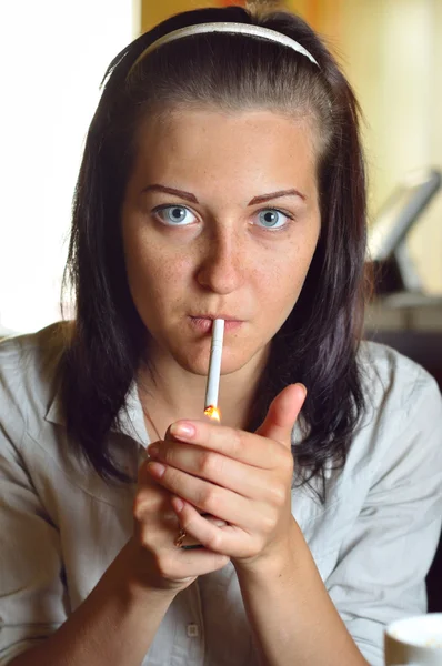 Une jeune femme allume une cigarette dans un café — Photo