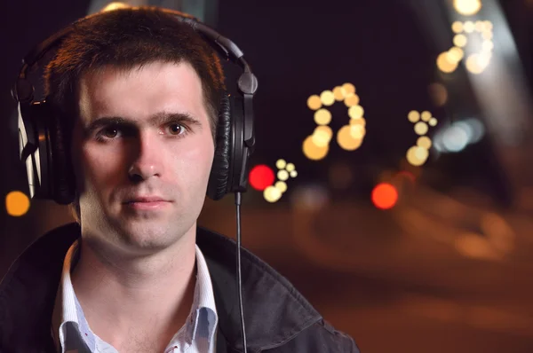 Hombre escuchando música en la calle nocturna de la ciudad — Foto de Stock