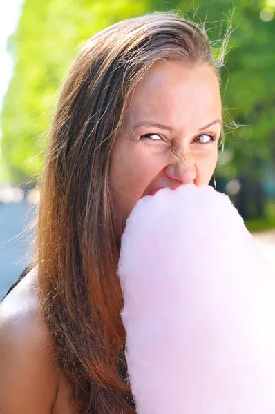 Joven hermosa mujer está comiendo hilo de azúcar en el parque — Foto de Stock