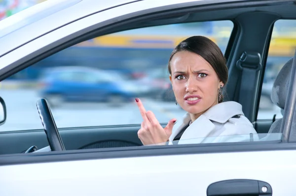 Angry woman in a car is showing her middle finger — Stock Photo, Image