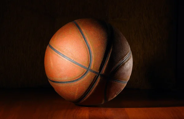 Basketball ball in dark on wooden floor — Stock Photo, Image