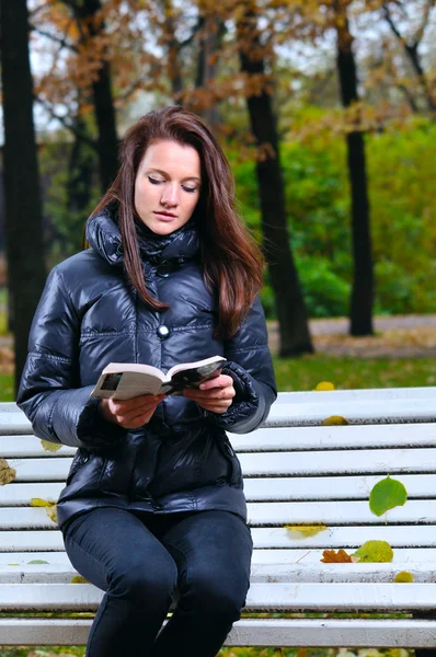 Mooie vrouw is sitiing in park en lezen — Stockfoto