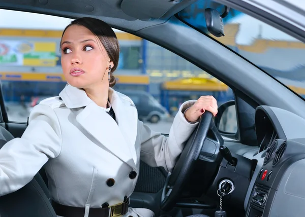 Mujer en un coche está mirando hacia atrás tratando de moverse hacia atrás — Foto de Stock