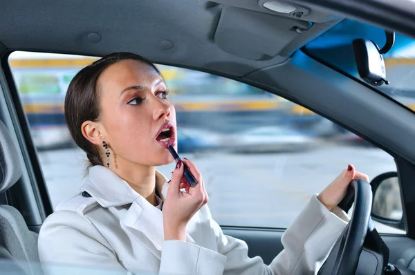 Mulher elegante está fazendo maquiagem em fuga em seu carro — Fotografia de Stock