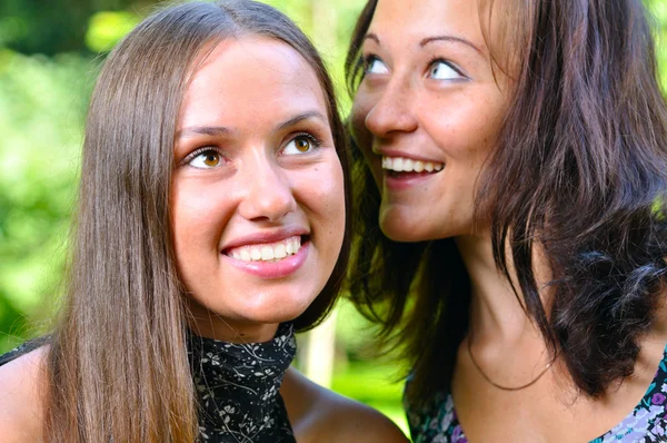 Two female friends are sharing secrets in summer park — Stock Photo, Image