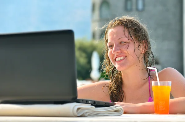Женщина использует ноутбук из бассейна рядом с отелем — стоковое фото