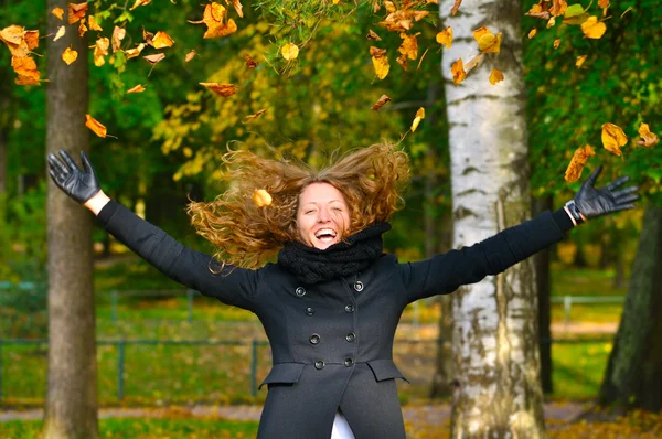 Donna felice sta gettando foglie secche autunno nel parco — Foto Stock