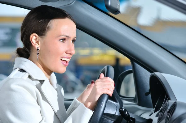 Mujer de negocios feliz en un coche está mirando a la cámara — Foto de Stock
