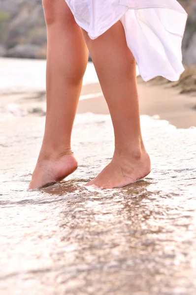 Female legs on sunrise beach — Stock Photo, Image