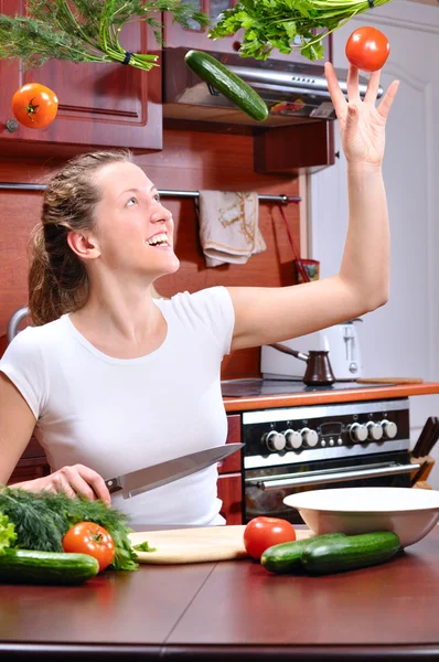 Happy woman is cooking salad out of flying vegetables — Stock Photo, Image