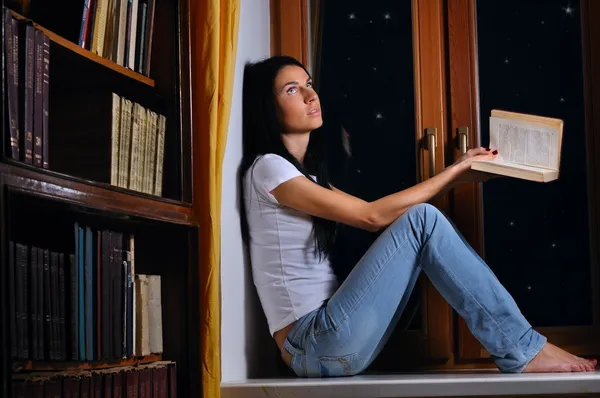 Mooie vrouw is zittend op een venster en dromen — Stockfoto