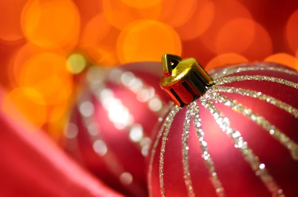 Palline decorative natalizie su seta rossa contro luci sfocate accese — Foto Stock