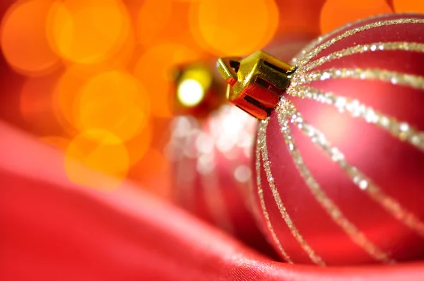Bolas decorativas de Navidad en seda roja contra las luces borrosas en —  Fotos de Stock