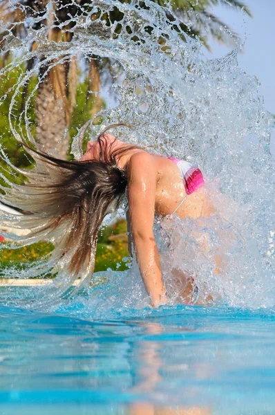 Slim woman is spectacularly jumping out of pool and shaking hair — Stock Photo, Image