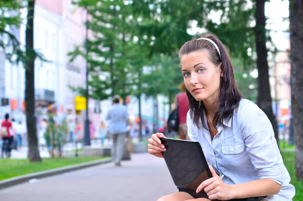 Bella donna è seduta in città con computer portatile e guardando ca — Foto Stock