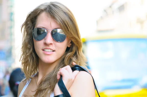 Молода усміхнена жінка на яскравій міській вулиці — стокове фото