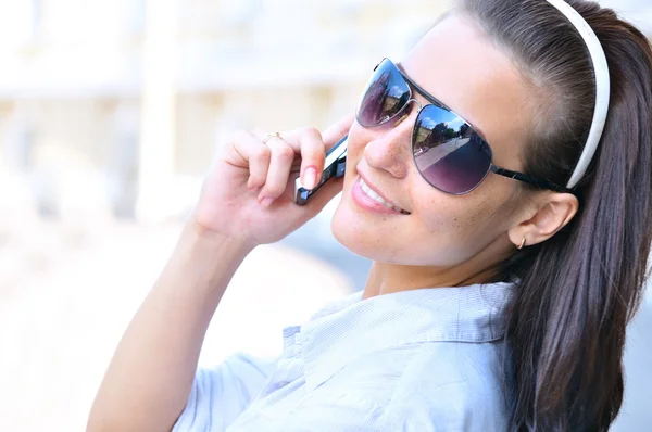 Щаслива жінка дивиться назад і розмовляє по телефону — стокове фото