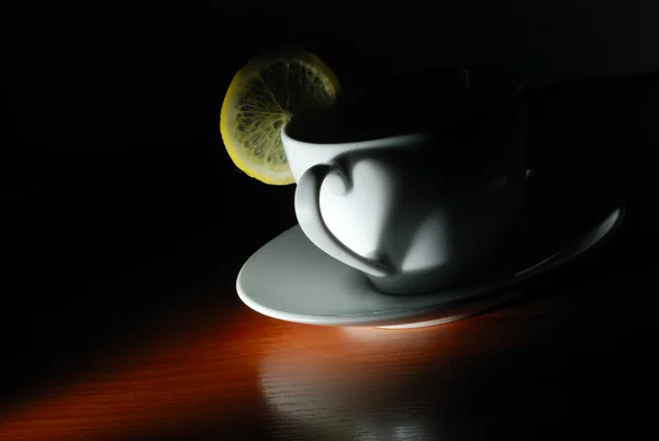 Cup with lemon in dark — Stock Photo, Image