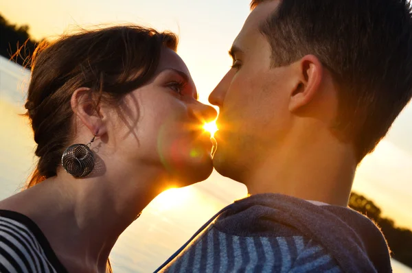 Jovem casal atraente está se beijando ao pôr do sol — Fotografia de Stock