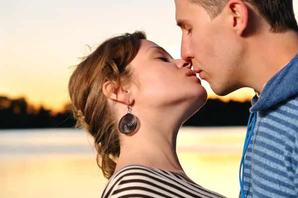 Молода приваблива пара цілується на заході сонця — стокове фото