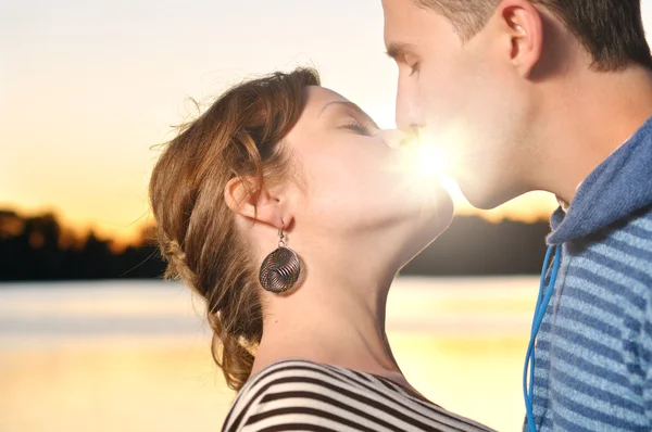 Молода приваблива пара цілується на заході сонця — стокове фото