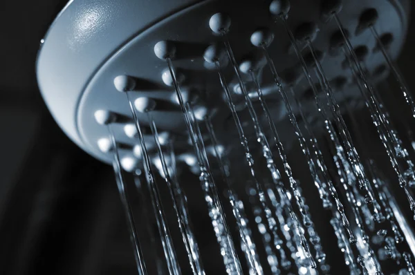 stock image Closeup view of water flowing out of shower in dark