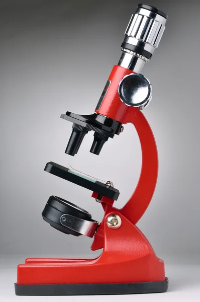 Red microscope on gray background — Stock Photo, Image